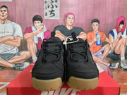 Front view of black Nike sneakers with lace-up closures, layered toe panels, and gum-colored soles.