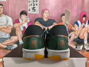 Rear view of black and dark green Nike basketball shoes with orange accents and white midsoles.