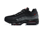 Side profile of a black and grey Nike Air Max 95 sneaker with a small red accent and visible cushioning units.