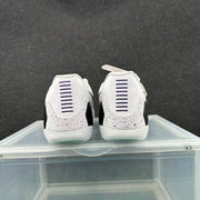 Rear view of white low-top basketball shoes with purple heel details and speckled heel panels