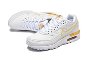 Pair of white and gold Nike Air Max lace-up sneakers.