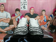 Front view of white lace-up basketball shoes with black geometric patterning and red accents.