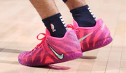 Pink and purple Nike basketball sneakers being worn, with contrasting Swoosh branding and textured side panels.