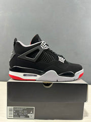 Side view of black and red Jordan Air Jordan 4 sneakers resting on a black shoebox; the box label shows a photographed sample in EU 41 and style code IX8180 001.