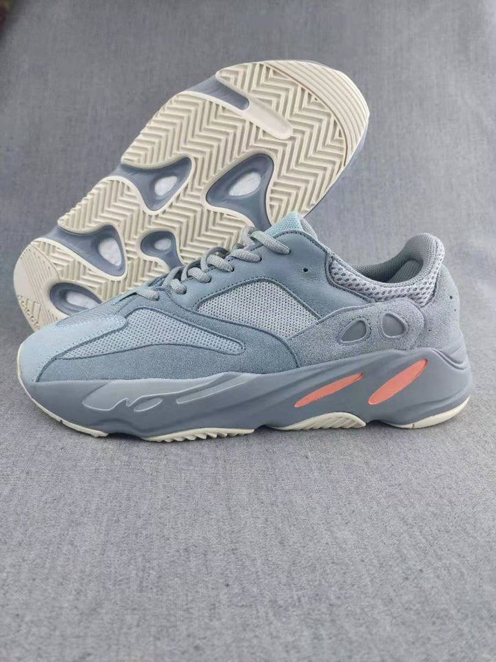 Side and outsole view of gray low-top sneakers with coral sole accents and a textured tread.