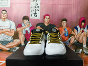 Front view of the shoes showing perforated white toes and patterned black-and-gold laces.