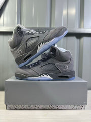 Two grey high-top sneakers displayed together, showing their side panels, lace areas, black midsoles, and translucent blue outsoles.
