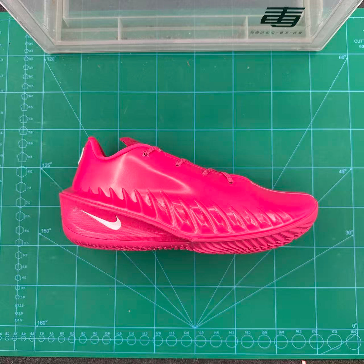 Side profile of a bright pink Nike basketball sneaker on a green measurement mat.