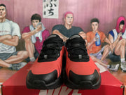Front view of black and red Nike sneakers showing the lace-up construction, black toe guards, and tongue branding.