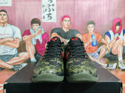 Front view of the pair showing black laces, camouflage toe boxes, red tongue branding, and olive-green soles.