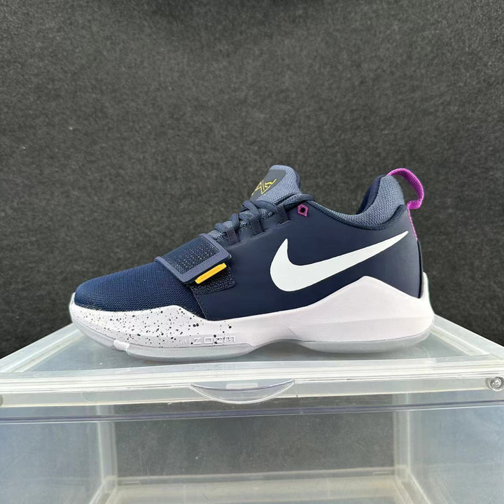 Side view of a deep blue and white Nike training sneaker with a forefoot strap, white Swoosh, speckled midsole, and pink heel pull tab