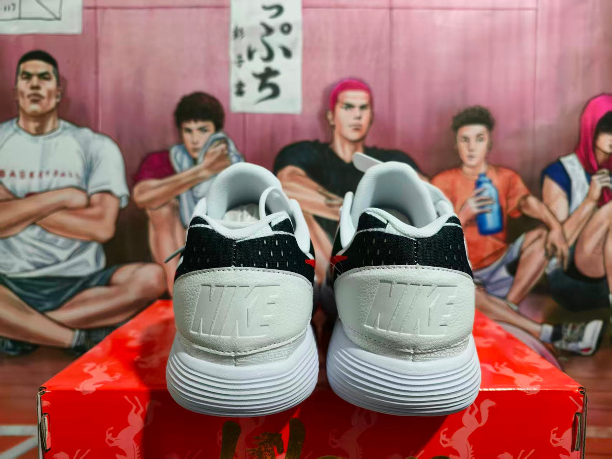 Rear view of white Nike sneakers with black heel panels, embossed branding, and layered white outsoles on a red box.