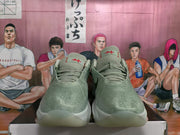 Front view of green basketball sneakers with red tongue details, textured uppers, and lace-up closures.