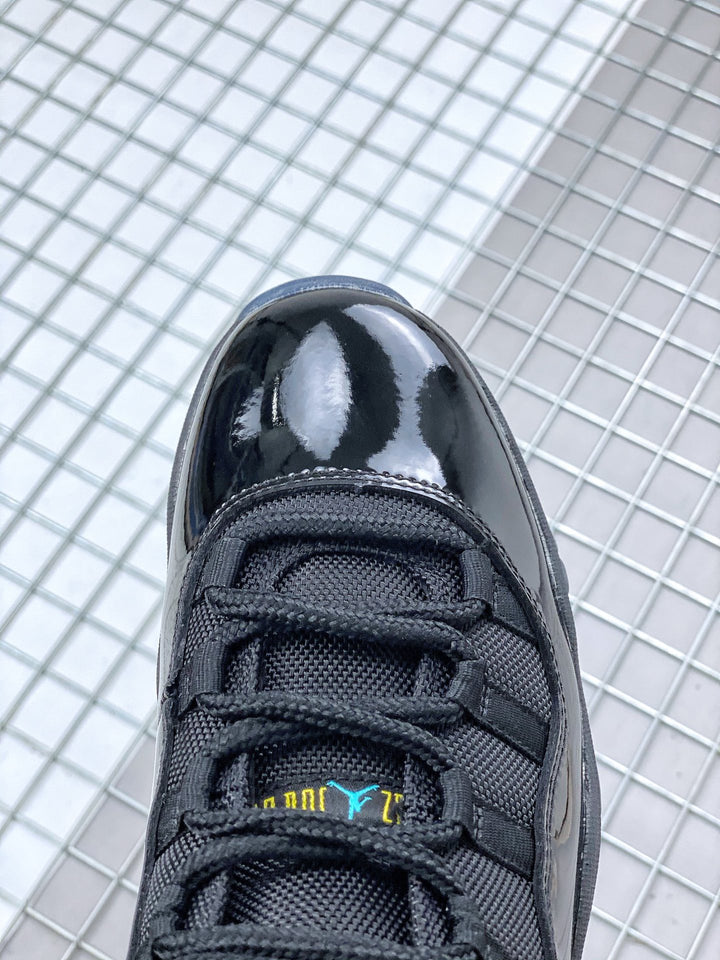 Close-up of the black sneaker toe box, black laces and tongue with blue and yellow branding details.