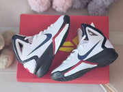 Pair of white, navy, black and red Nike Hyperdunk 2010 kids’ high-top basketball shoes on a red box
