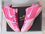 Pair of pink basketball shoes displayed on a dark shoe box