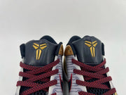 Top close-up of two shoe tongues with gold Kobe logos and red-and-black laces.