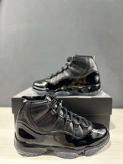 Close view of a black high-top sneaker showing the lacing system, glossy side panels, and translucent outsole.