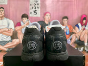 Rear view of the sneakers showing black heel sections with EYBL graphics and speckled black soles.