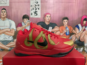 Side profile of a red Nike basketball sneaker with a black Swoosh, textured gold graphic overlay, gold toe accent, and black outsole.