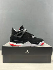 Side profile of a black Jordan Air Jordan 4 sneaker displayed on a black shoebox.