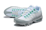 Angled view of a pair of white, grey, and green Nike Air Max 95 TT sneakers