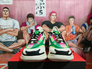 Front view of Under Armour SlipSpeed sneakers in butter white with green, pink, black and neon yellow accents, displayed on a shoe box.