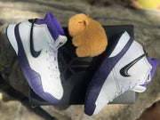 Top-down view of a pair of white and purple high-top sneakers positioned over a dark shoebox.