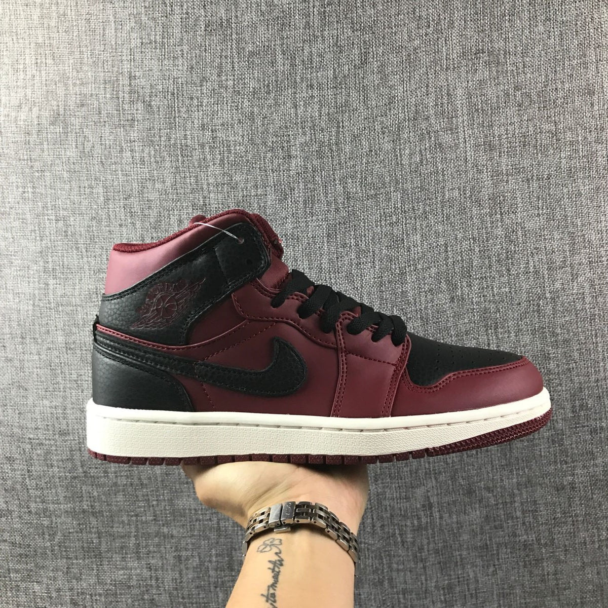 Side view of a burgundy and black Jordan high-top sneaker with a white midsole.