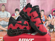Angled view of a pair of red and black Nike sneakers showing the side panels and soles