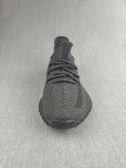 Front view of a black knit sneaker with black laces and a rounded toe.