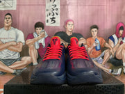 Front view of the pair showing red laces and tongues, perforated toe panels, dark navy uppers, and contrasting outsole details.