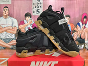 Angled view of black Nike sneakers displaying the side construction, pull tabs, translucent cushioning units, and gum-colored outsoles.
