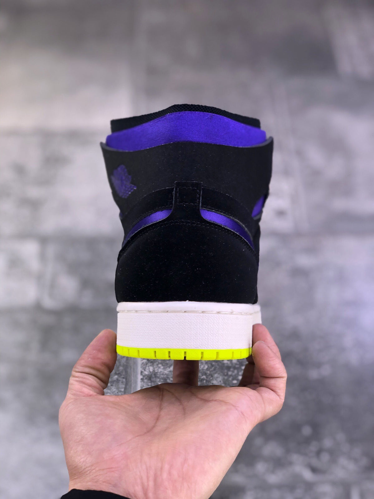 Rear view of a black and purple high-top sneaker with a white midsole and bright volt outsole edge.