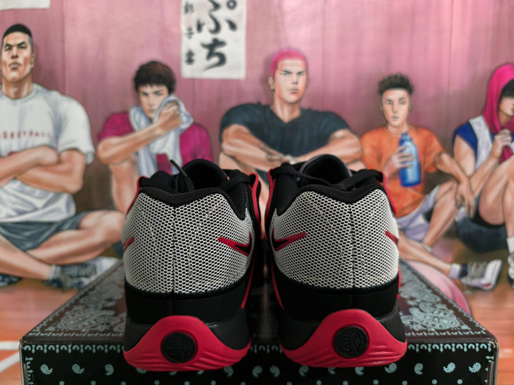 Rear view of black, white, and red Nike basketball sneakers showing mesh-style heel panels and red outsole sections.