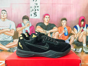 Black and gold low-top basketball sneakers shown from the side on a red box