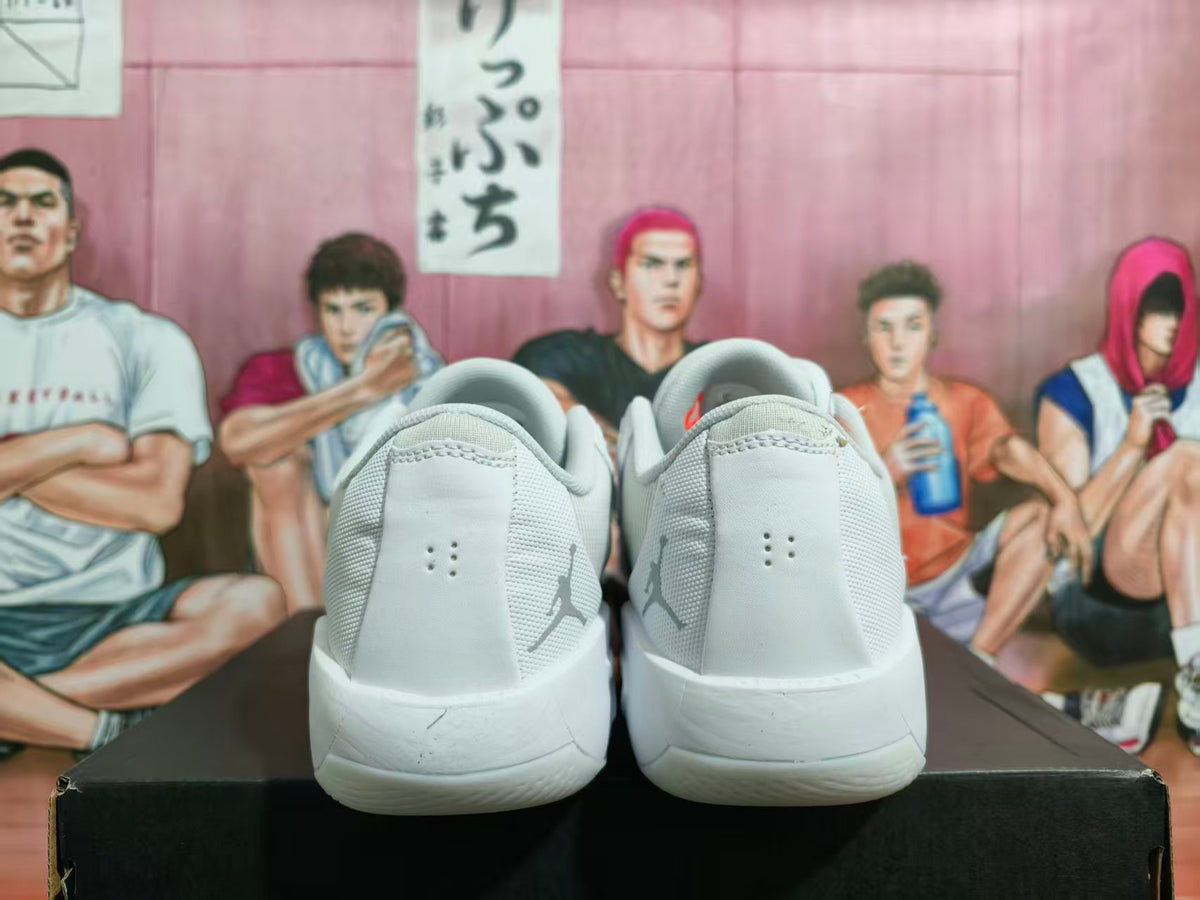 Rear view of white and light gray Jordan sneakers showing heel Jumpman logos and a white outsole.