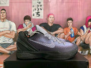 Side profile of one black and purple basketball sneaker showing the textured upper, side swoosh, layered black sole, and cushioning section.