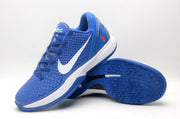 Angled view of a blue basketball sneaker resting over another shoe, showing the textured upper and outsole pattern.