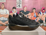 Side view of a black low-top basketball sneaker showing textured panels and a translucent outsole.