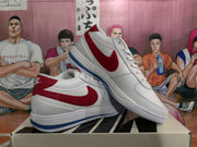 Pair of white Nike sneakers displayed at an angle, showing red Swooshes and blue outsole accents.
