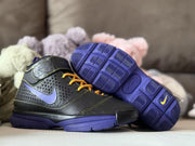 Angled view of one sneaker beside its patterned purple outsole, highlighting the black upper and purple accents.