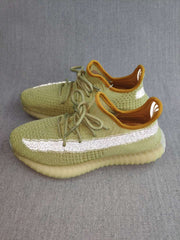 Pair of green Yeezy 350 V2-style sneakers showing reflective side stripes, tonal laces, amber collars, and translucent soles.