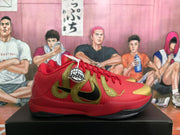 Side profile of a red Nike basketball sneaker with large gold and black side detailing and a gold toe accent.