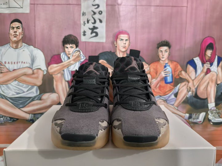 Front view of brown and dark camouflage basketball sneakers with black laces and translucent gum-colored outsoles.