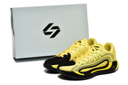 Yellow and black sneaker pair displayed beside a shoe box with a stylized black logo.
