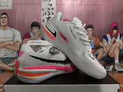Angled view of a pair of white Nike basketball shoes showing textured uppers and pink and orange details.