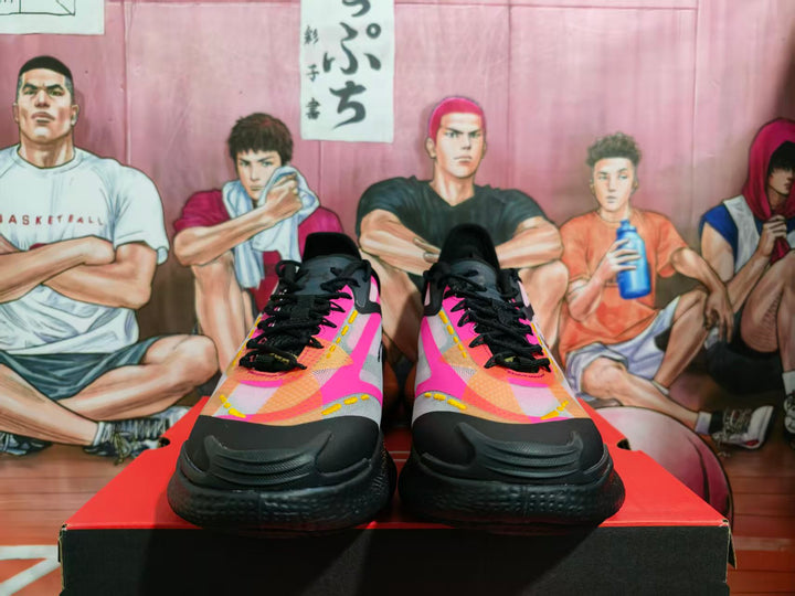 Pair of black, pink, gray, and orange Under Armour basketball sneakers shown from the front on a shoebox.