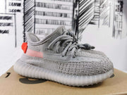 Side view showing the gray upper, pink side stripe, orange heel accent, and translucent sole.