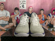 Front view of white Nike basketball shoes with textured uppers, white laces, and blue-purple collar details.